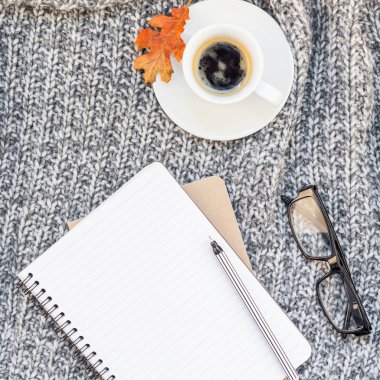 Yaratıcı bir şekilde sonbahar düz ek yükü üstten görünüm şık ev çalışma alanı defter kahve fincanı sıcak gri örgü ekose arka plan kopya alanı ile yatıyordu. Sonbahar sezonu şablon kadınsı blog sosyal medya için