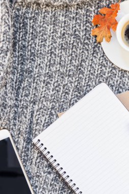 Yaratıcı sonbahar düz ek yükü üstten görünüm şık ev çalışma alanı smartphone defter kahve Kupası rahat gri örgü ekose arka plan kopya alanı ile yatıyordu. Sonbahar sezonu şablon kadınsı blog sosyal medya için