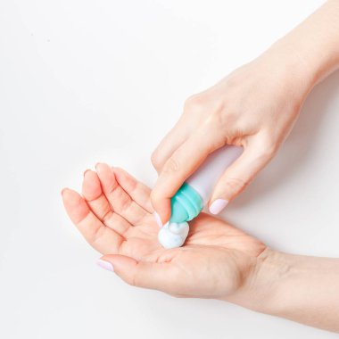 Yaratıcı kare görüntü kadın minimalizm tarzı beyaz arka plan üzerinde kopya alanı ile kozmetik krem losyon ile el cildi nemlendirici. Kavram şablon kadınsı blog sosyal medya güzellik kavramı