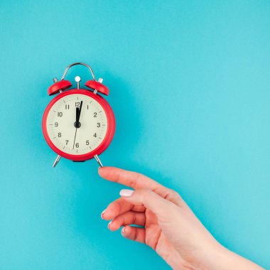 Yaratıcı düz yatıyordu kavramı kırmızı vintage çalar saat üzerinde kare parlak mavi turkuaz tutan kadın el üst görünümünü renk Kağıt arka plan kopya alanı ile en az tarzı, metin için şablon