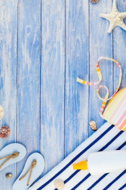 Yaratıcı düz yaz seyahat tatil kavramı yatıyordu. Plaj havlusu güneş kremi şişe mayo deniz kabuklarını denizyıldızı üstten görünüm kopya alanı mockup şablon metin pastel mavi ahşap plakalar zemin üzerine