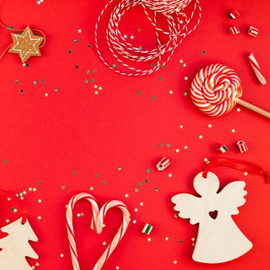 Yeni yıl veya Noel dekorasyon düz üstten görünüm Xmas tatil kutlaması el yapımı dekor Ahşap oyuncaklar tatlılar altın yıldız kırmızı Kağıt arka plan üzerinde parıldayan yatıyordu. Kare şablon çerçeve tebrik kartı tasarımı
