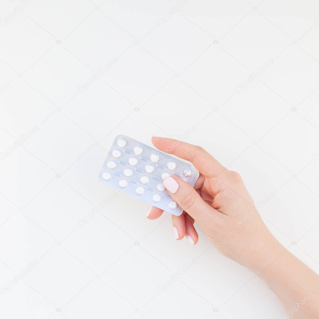 Woman hand with pastel manicure polish holding pills in blister isolated on white background with copy space. Square Template for feminine beauty blog social media. Female healthcare concept