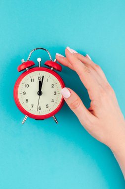 Yaratıcı düz yatıyordu kavramı kırmızı vintage çalar saat parlak mavi turkuaz üzerinde tutan kadın el üst görünümünü renk Kağıt arka plan kopya alanı ile en az tarzı, metin için şablon