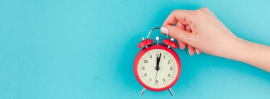 Yaratıcı düz yatıyordu kavramı kırmızı vintage çalar saat parlak mavi turkuaz üzerinde tutan kadın el üst görünümünü renk Kağıt arka plan kopya alanı ile minimal tarzda uzun geniş afiş