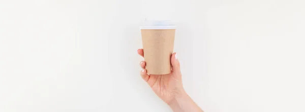 Long wide banner mock up of woman hand holding craft paper coffee cup with copy space isolated on white background in minimalism style. Template for feminine blog, social media
