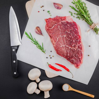 Yaratıcı üstten görünüm taze çiğ sığır eti striploin biftek biberiye kekik otlar sarımsak biber mantar et siyah arka plan ile kopya alanı düz yatıyordu. Kare kavramı yemek yiyecek et hazırlama