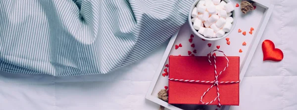 創造的なトップは フラット レイアウト枠生活ロマンチックな構成を表示します ホット チョコレート マシュマロ マグカップ赤いギフト心ベッド コンセプト バレンタイン休日朝の自然光でトレイをカカオ コーヒー長い広いバナー — ストック写真