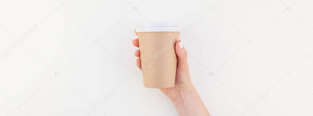 Long wide banner mock up of woman hand holding craft paper coffee cup with copy space isolated on white background in minimalism style. Template for feminine blog, social media