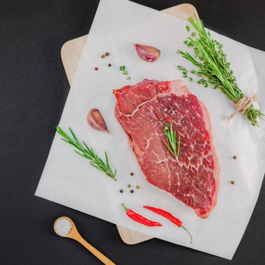 Yaratıcı üstten görünüm taze çiğ sığır eti striploin biftek biberiye kekik otlar sarımsak biber mantar et siyah arka plan ile kopya alanı düz yatıyordu. Kare kavramı yemek yiyecek et hazırlama