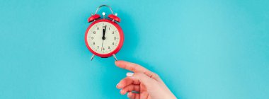 Yaratıcı düz yatıyordu kavramı kırmızı vintage çalar saat parlak mavi turkuaz üzerinde tutan kadın el üst görünümünü renk Kağıt arka plan kopya alanı ile minimal tarzda uzun geniş afiş