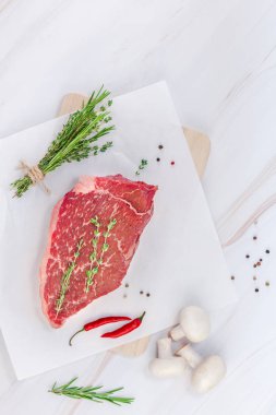 Yaratıcı üstten görünüm taze çiğ sığır eti striploin biftek biberiye kekik otlar sarımsak biber mantar beyaz mermer masa arka plan kopya alanı ile üzerinde düz yatıyordu. Gıda hazırlama pişirme kavramı