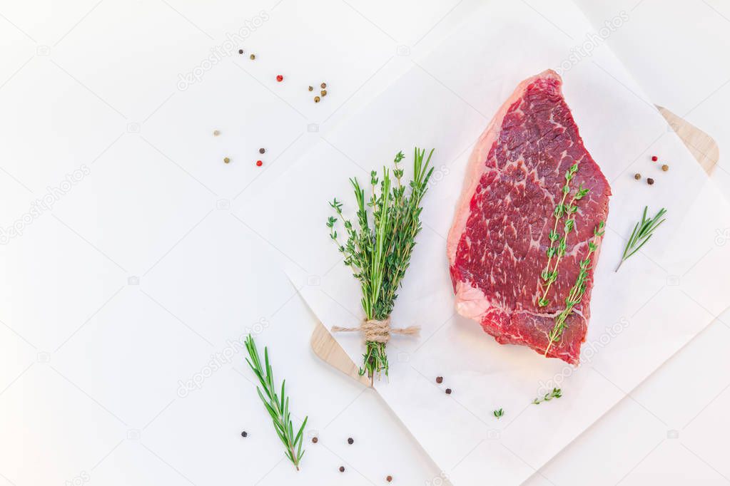 Creative Top view flat lay of fresh raw beef meat striploin steak with rosemary thyme herbs garlic pepper meat mushrooms on white background with copy space. Food meat preparation cooking concept