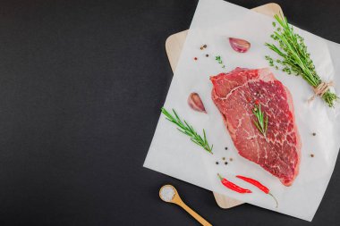 Creative Top view flat lay of fresh raw beef meat striploin steak with rosemary thyme herbs garlic meat pepper mushrooms on black background with copy space. Food meat preparation cooking concept clipart