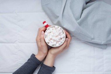 Yeni yıl veya Noel düz üstten görünüm sıcak kakao kahve çikolata şekerleme kupa kadın elinde ile Xmas tatil kutlaması ışıklar yatağa yatırın. Kavram blog sosyal medya 2019