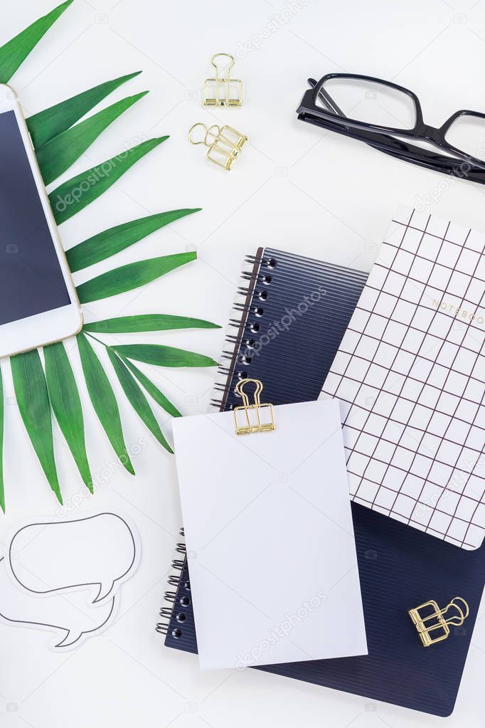 Top view flat lay office workspace desk styled design office supplies tropical palm leaves smartphone copy space black white background. Template office feminine blog social media