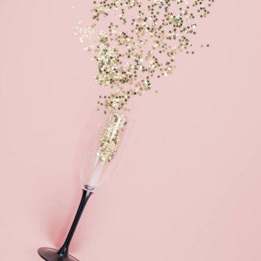 Yeni yıl Noel en iyi görünüm düz altın yıldız konfeti kopya alanı bin yıllık pembe renkli kağıt arka plan en az stil şablonu kadınsı blog sosyal medya kartpostalı dökülür şampanya kadehi yatıyordu