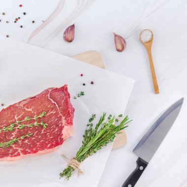Yaratıcı en iyi görünüm düz yatıyordu taze çiğ sığır eti striploin biftek biberiye kekik otlar sarımsak biber mantar et beyaz mermer masa arka plan kopya alanı. Kare kavramı yemek yiyecek et hazırlama