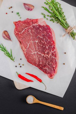 Yaratıcı üstten görünüm taze çiğ sığır eti striploin biftek biberiye kekik otlar sarımsak biber mantar kopya alanı siyah zemin üzerine düz yatıyordu. Gıda hazırlama pişirme kavramı