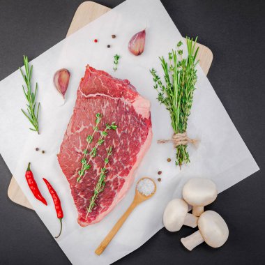 Yaratıcı üstten görünüm taze çiğ sığır eti striploin biftek biberiye kekik otlar sarımsak biber mantar et siyah arka plan ile kopya alanı düz yatıyordu. Kare kavramı yemek yiyecek et hazırlama