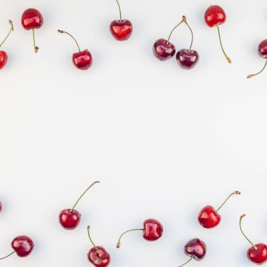 Üstten görünüm taze olgun kiraz desen düzeninin en az tarzında beyaz arka plan üzerinde izole kopya alanı ile kare. Yaz eğlenceli ve sağlıklı beslenme kavramı. Metin veya gıda tasarımınız için şablon