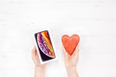 Berlin, Almanya - 09 Aralık 2018: Beyaz ahşap arka plan karşı son Apple iphone Xs smartphone kutusu ve kırmızı kalp holding kadın eller. Sevgililer günü hediyesi kavramı kopya alanı ile