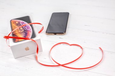Berlin, Almanya - 09 Aralık 2018: son Apple iphone Xs smartphone kutusu ve şerit kırmızı kalp Beyaz ahşap arka plan karşı. Sevgililer günü hediyesi kavramı kopya alanı ile