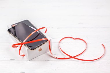 Berlin, Almanya - 09 Aralık 2018: son Apple iphone Xs smartphone kutusu ve şerit kırmızı kalp Beyaz ahşap arka plan karşı. Sevgililer günü hediyesi kavramı kopya alanı ile