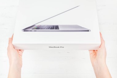 Berlin, Almanya - 09 Aralık 2018: en son Apple Macbook Pro dizüstü bilgisayar kutusu beyaz ahşap arka plan karşı holding kadın eller. Unboxing üstten görünüm kavramı kopya alanı ile
