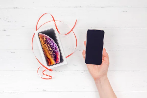 白い木製の背景に対して最新のアップル Iphone スマート フォン ボックスを持つベルリン ドイツ 2018 女性の手 コピー スペースでバレンタインの日現在の概念 — ストック写真