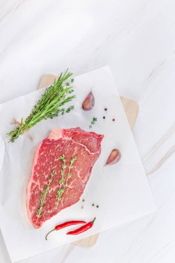 Yaratıcı üstten görünüm taze çiğ sığır eti striploin biftek biberiye kekik otlar sarımsak biber mantar beyaz mermer masa arka plan kopya alanı ile üzerinde düz yatıyordu. Gıda hazırlama pişirme kavramı