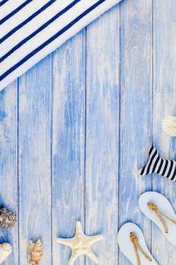 Yaratıcı düz yaz seyahat tatil kavramı yatıyordu. Deniz kabuklarını ve deniz yıldızı kopya alanı rustik tarzı çerçeve şablonu metin pastel mavi ahşap plakalar zemin üzerine üstten görünüm havlu Flip floplar