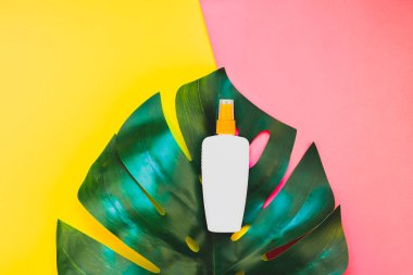 Tropikal orman palmiye monstera yaprakları ve güneş koruyucu boş şişe mockup parlak sarı ve pembe çift ton kağıt arka plan üzerinde. Metin için yaratıcı düz yatıyordu kavramı şablon yaz tatil