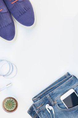 Düz beyaz arka plan kopya alanı ile kulaklıktan süet ayakkabı, kot, bilezik ve smartphone yatırın. Kadın rahat kıyafet havai görünümü. Trendy hipster bak üstten görünüm