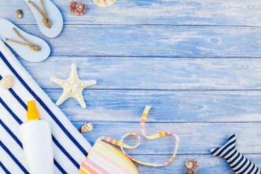 Yaratıcı düz yaz seyahat tatil kavramı yatıyordu. Plaj havlusu güneş kremi şişe mayo deniz kabuklarını denizyıldızı üstten görünüm kopya alanı mockup şablon metin pastel mavi ahşap plakalar zemin üzerine