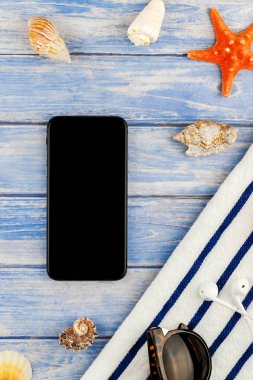 Yaratıcı düz yaz seyahat tatil kavramı yatıyordu. Plaj havlusu smartphone deniz kabuğu denizyıldızı üstten görünüm Kopyala yer mockup template metin için pastel mavi ahşap plakalar zemin üzerine