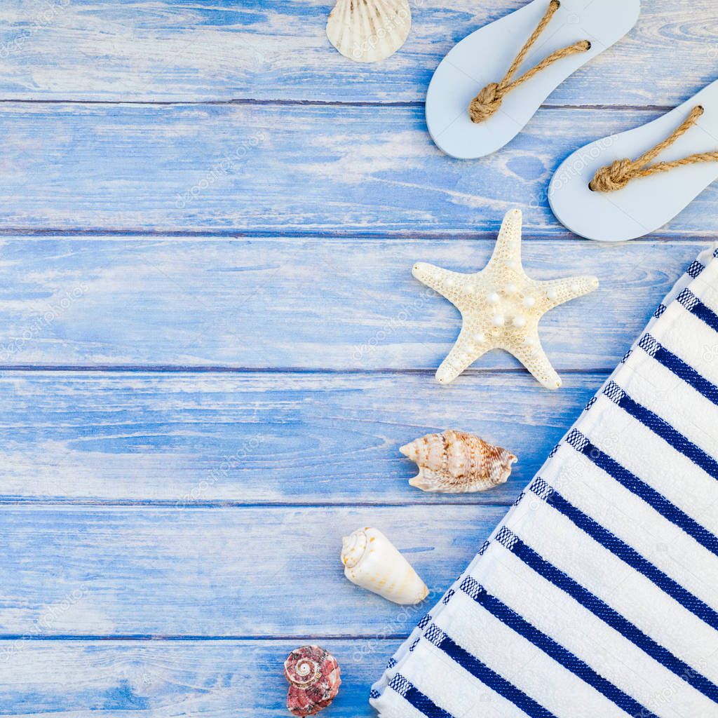 Creative flat lay concept summer travel vacations. Top view of towel flip flops seashells and starfish on pastel blue wooden planks background with copy space rustic style square frame template text