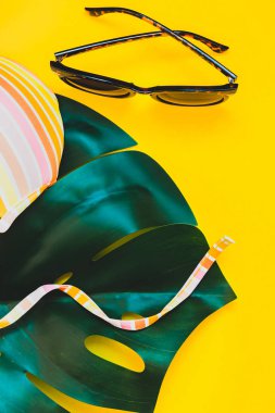 Tropikal orman palm monstera, güneş gözlüğü ve parlak sarı kağıt arka plan bir kadının mayo üstüne bırakır. Metin için yaratıcı düz yatıyordu kavramı şablon yaz tatil