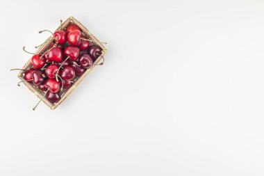 Yaratıcı üstten görünüm taze olgun kiraz kopya alanı ile küçük bir sepet içinde beyaz arka plan en az stili izole. Yaz eğlenceli ve sağlıklı beslenme kavramı. Metin veya gıda tasarımınız için şablon