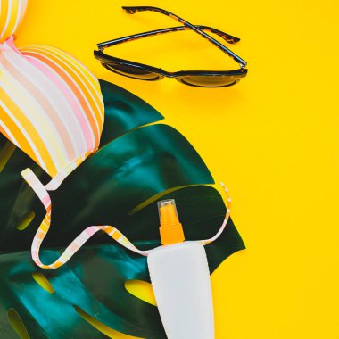 Tropikal orman palm monstera bırakır, güneş gözlüğü, Güneş kremi boş şişe mockup ve kadının mayo üstüne parlak kare Kağıt arka plan sarı. Yaz tatil yaratıcı düz yatıyordu kavramı şablonu