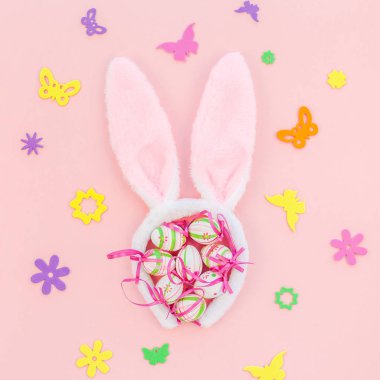 Yaratıcı Top View düzlük tatil kompozisyonu. Paskalya yumurtaları tavşan kulakları. Pembe kağıt arka plan üzerinde bahar çiçekleri.