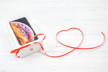 Berlin, Almanya - 09 Aralık 2018: son Apple iphone Xs smartphone kutusu ve şerit kırmızı kalp Beyaz ahşap arka plan karşı. Sevgililer günü hediyesi kavramı kopya alanı ile