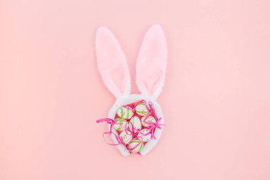 Yaratıcı Top View düzlük tatil kompozisyonu. Paskalya yumurtaları tavşan kulakları. Pembe kağıt arka plan üzerinde bahar çiçekleri.