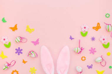 Yaratıcı Top View düzlük tatil kompozisyonu. Paskalya yumurtaları tavşan kulakları. Pembe kağıt arka plan üzerinde bahar çiçekleri.