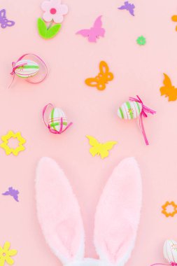 Yaratıcı Top View düzlük tatil kompozisyonu. Paskalya yumurtaları tavşan kulakları. Pembe kağıt arka plan üzerinde bahar çiçekleri.