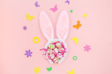 Yaratıcı Top View düzlük tatil kompozisyonu. Paskalya yumurtaları tavşan kulakları. Pembe kağıt arka plan üzerinde bahar çiçekleri.