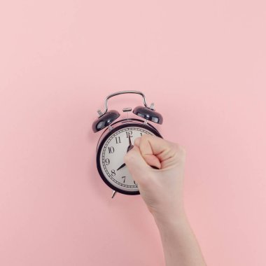 Yaratıcı düz sabah zaman duygular kadın el Siyah vintage çalar saat pastel bin yıllık pembe renkli kağıt arka plan kopya alanı en az tarzı kare şablonuyla tutarak en iyi görünümünü kavramı yatıyordu.