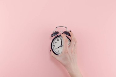 Yaratıcı düz sabah zaman duygular kavramı en iyi siyah vintage çalar saat pastel bin yıllık pembe renkli kağıt arka plan metin için kopya alanı en az stil şablonu ile birlikte tutan kadın el görünümünü yatıyordu.