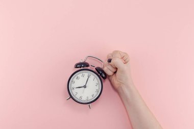 Yaratıcı düz sabah zaman duygular kavramı en iyi siyah vintage çalar saat pastel bin yıllık pembe renkli kağıt arka plan metin için kopya alanı en az stil şablonu ile birlikte tutan kadın el görünümünü yatıyordu.