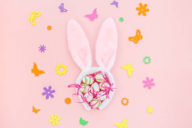Yaratıcı Top View düzlük tatil kompozisyonu. Paskalya yumurtaları tavşan kulakları. Pembe kağıt arka plan üzerinde bahar çiçekleri.